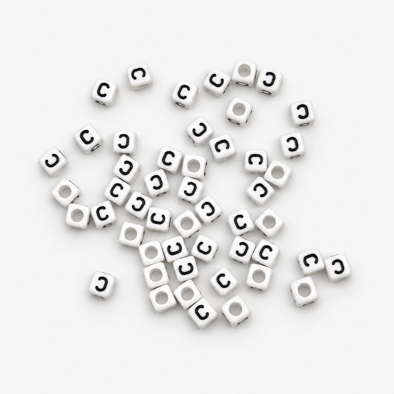 A pile of small white cube-shaped beads with a black letter 'C' printed on one side, scattered on a plain white background.