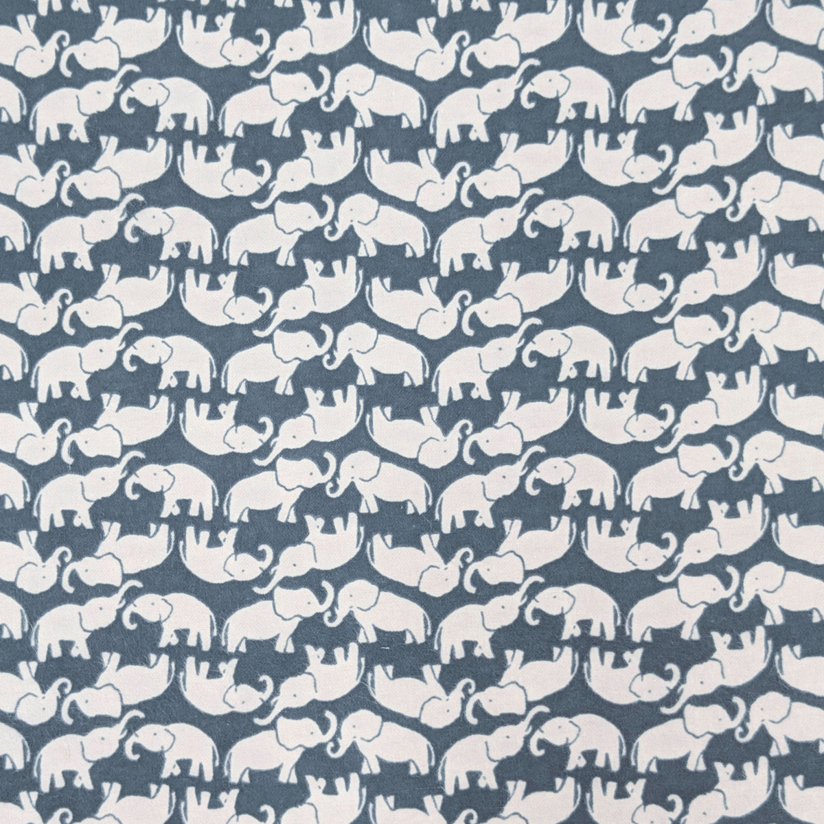 A close-up of a fabric pattern featuring repeating white elephant silhouettes on a muted slate blue background.