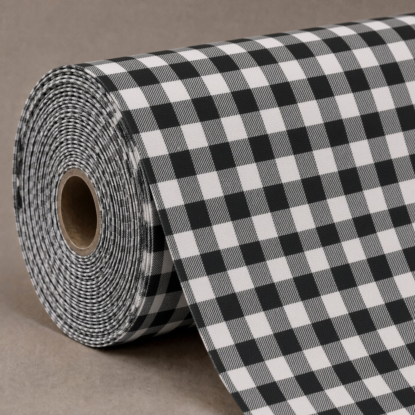 A roll of black and white gingham fabric or wrapping paper, partially unrolled to show the checkered pattern, set against a neutral brown background.
