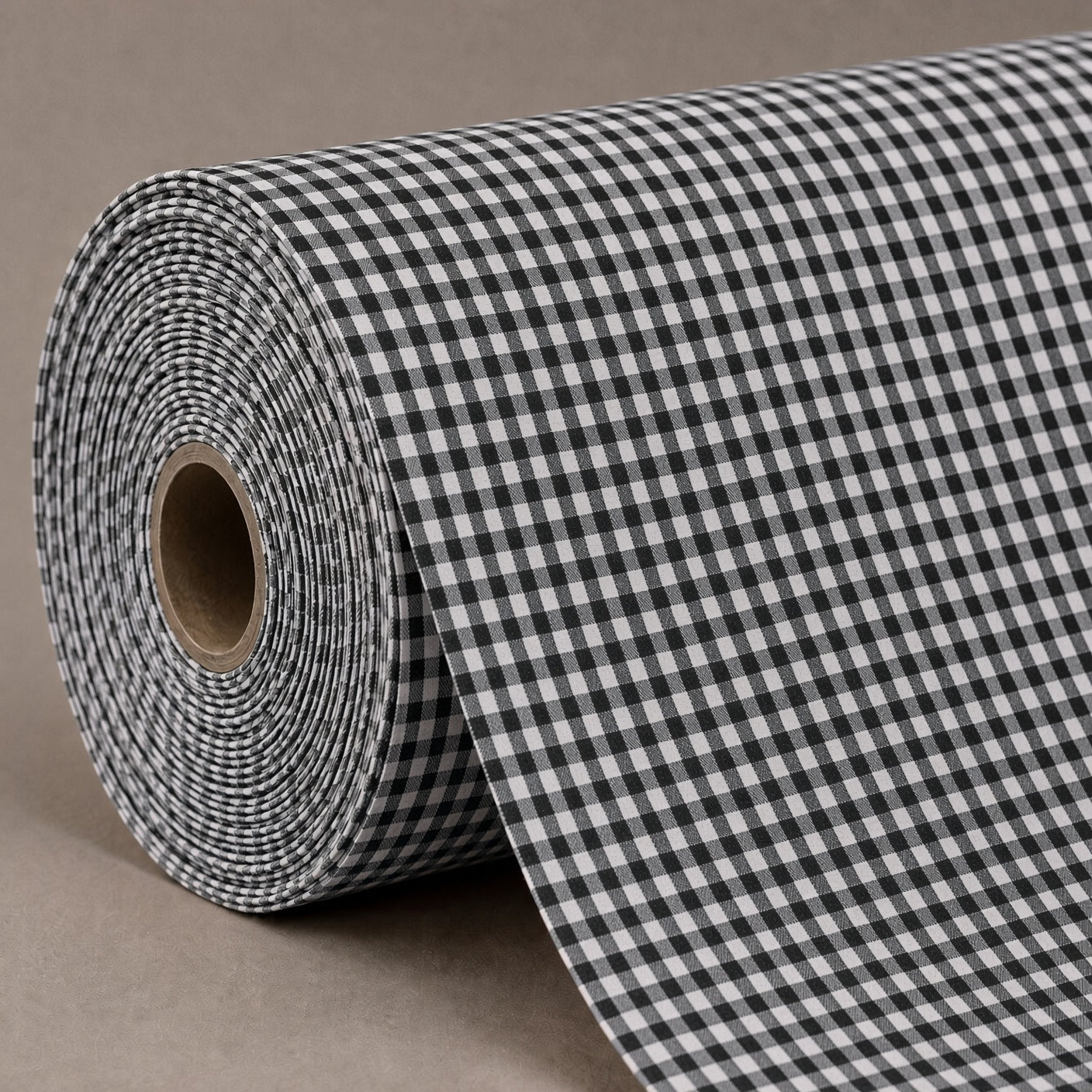 A roll of black and white gingham patterned fabric or wallpaper, partially unrolled to show the checkered pattern and cardboard core, set against a neutral taupe background.