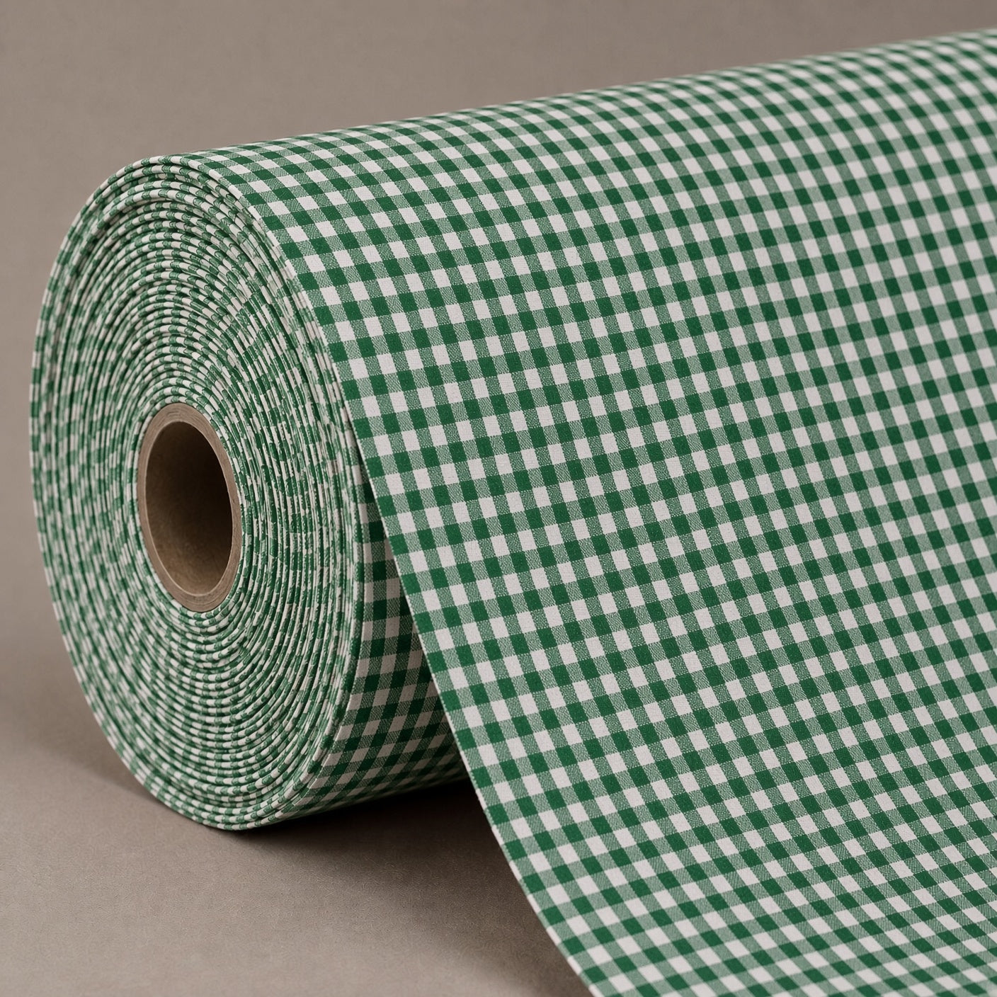 A roll of green and white gingham patterned material, partially unrolled, set against a solid neutral gray background.