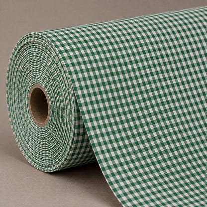A roll of green and white gingham patterned material, partially unrolled, set against a solid neutral gray background.