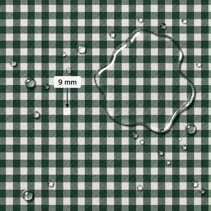 A close-up of a green and white gingham fabric surface with water droplets and a large transparent water puddle on top. A label reads “9 mm” with an arrow pointing to the puddle, indicating pattern scale.
