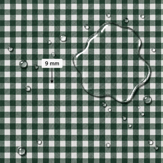 A close-up of a green and white gingham fabric surface with water droplets and a large transparent water puddle on top. A label reads “9 mm” with an arrow pointing to the puddle, indicating pattern scale.