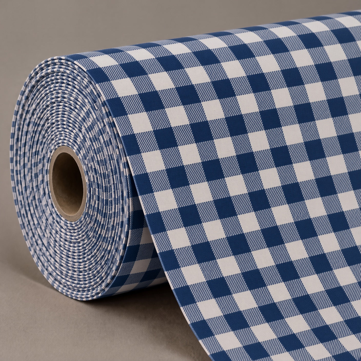 A roll of blue and white gingham fabric or wrapping paper, partially unrolled to show its checkered pattern and cardboard core, set against a neutral gray background.