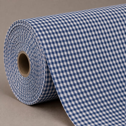 A roll of blue and white gingham patterned fabric or wrapping paper, partially unrolled, set against a neutral gray background.