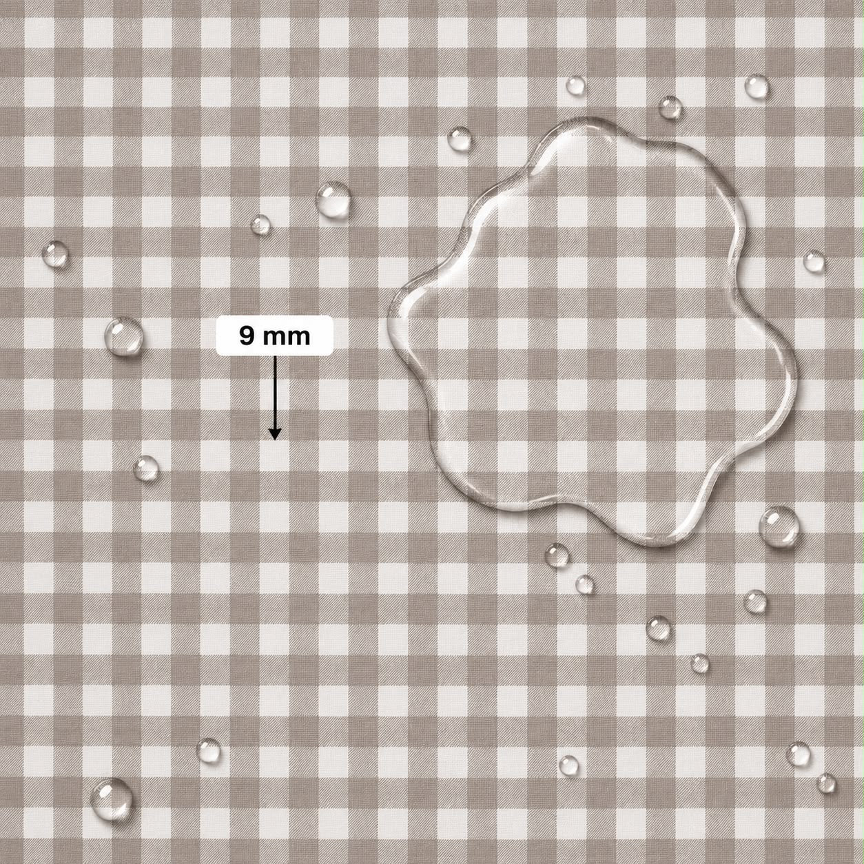 A close-up of a beige and white gingham fabric surface with scattered clear water droplets and a large transparent puddle of water on the right. A label reading '9 mm' with an arrow points to the puddle, indicating fabric scale