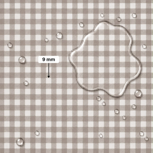 A close-up of a beige and white gingham fabric surface with scattered clear water droplets and a large transparent puddle of water on the right. A label reading '9 mm' with an arrow points to the puddle, indicating fabric scale