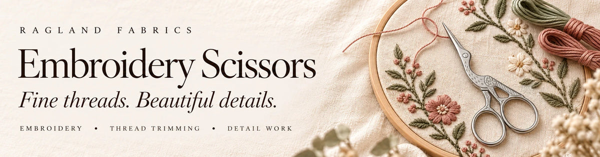 Ragland Fabrics Embroidery Scissors — silver stork scissors beside delicate botanical embroidery on ivory linen.