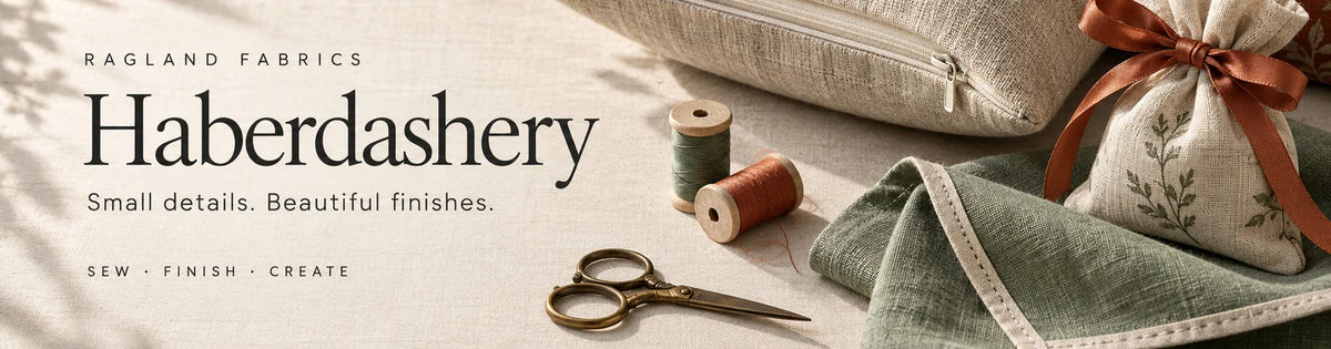Haberdashery — Small details. Beautiful finishes. A zipped linen cushion, bound sage seam and ribbon-tied fabric pouch with sewing thread and scissors.