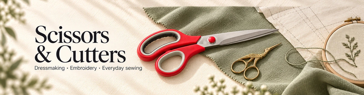 Scissors and cutters for dressmaking, embroidery and everyday sewing, with red fabric shears and golden embroidery scissors on sage fabric.