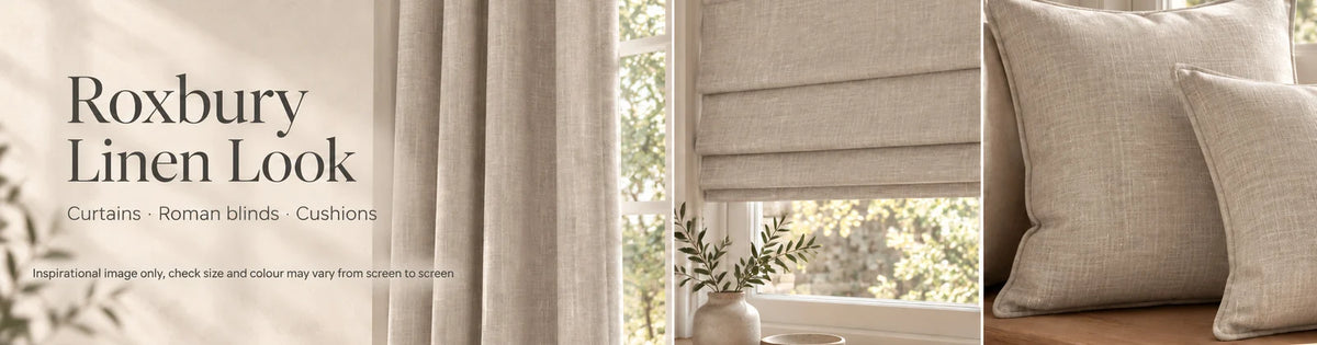 Roxbury Linen Look fabric shown as curtains, a Roman blind and scatter cushions in a warm neutral interior.